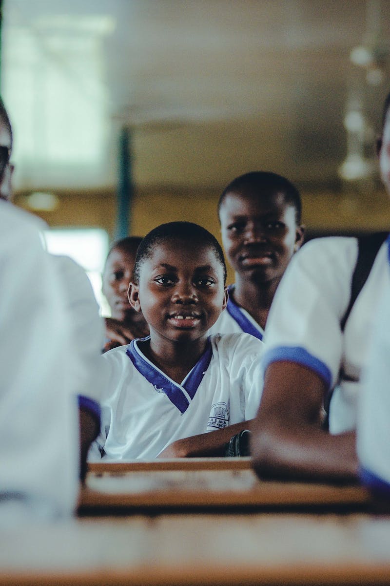A group of Nigerian schoolchildren in uniform sitting in a classroom, engaging in learning.